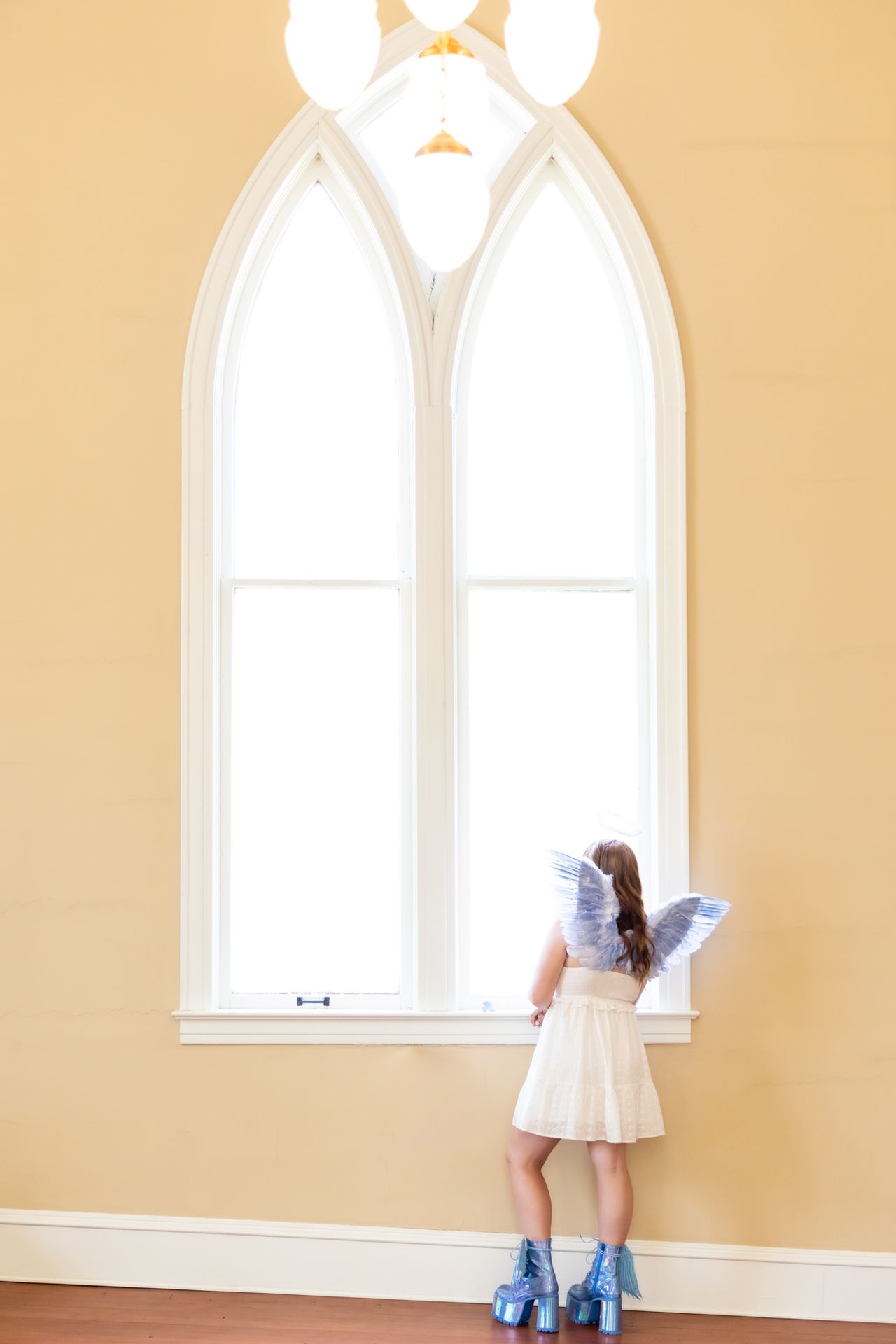 A women is wearing wings and is looking outside the window